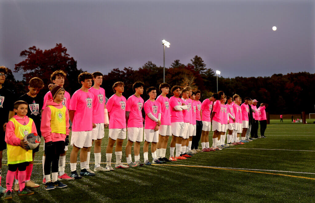 Underneath a nearly full moon, the Acton-Carlisle boys soccer team stands for the national anthem before playing Lincoln-Sudbury.