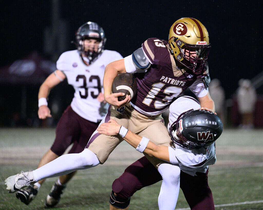 The Patriots’ John Ryan (No. 13) fights off the tackle of Westford Academy’s Cameron Croom (No. 1) on October 16. Photo by Jon Straggas