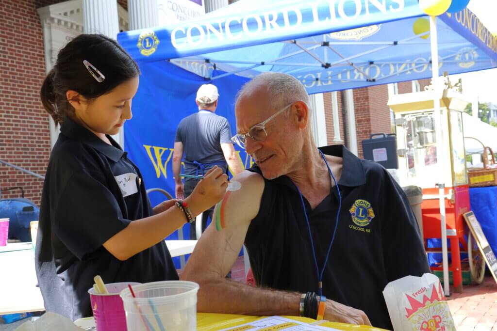 Dan Reilly gets a rainbow painted on his arm by Lian Reed. He also got a temporary tattoo of a lion. Photo: Trace Salzbrenner/The Acton Bridge