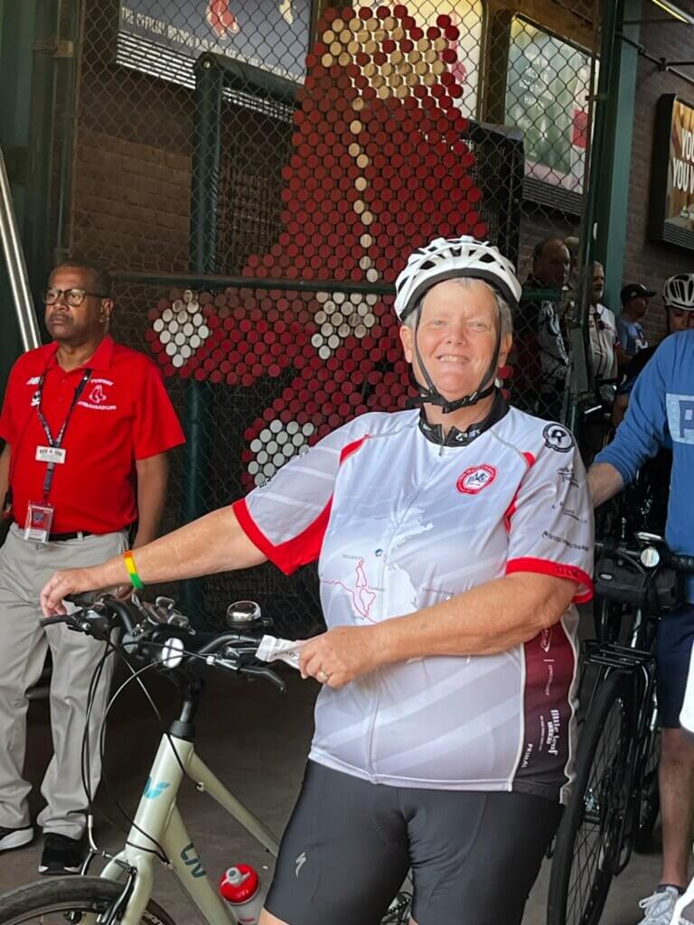 Liz Crowell in Fenway Park in 2023, participating in that year’s Pan-Mass Challenge. Flynn says she will sometimes wear Crowell’s old cycling jersey when she trains. Courtesy photo