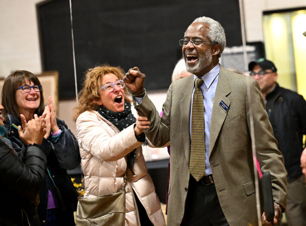 An elated Michael Williams, right, celebrates with supporters after winning a seat on the School Committee during an election night party at the Acton Armory on Tuesday, April 8, 2025. Ken McGagh/The Acton Bridge