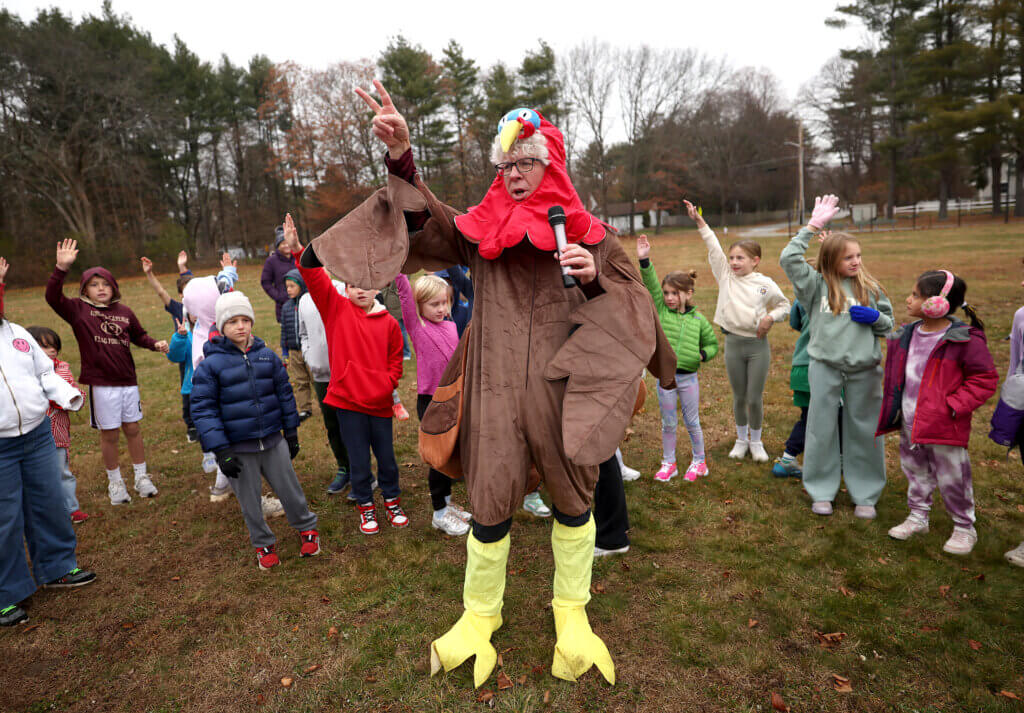 Willard Elementary School principal Matt Lucey takes to the wireless microphone as students gather for the annual pre-Thanksgiving Turkey Trot on Friday, November 21, 2025. Ken McGagh/The Acton Bridge