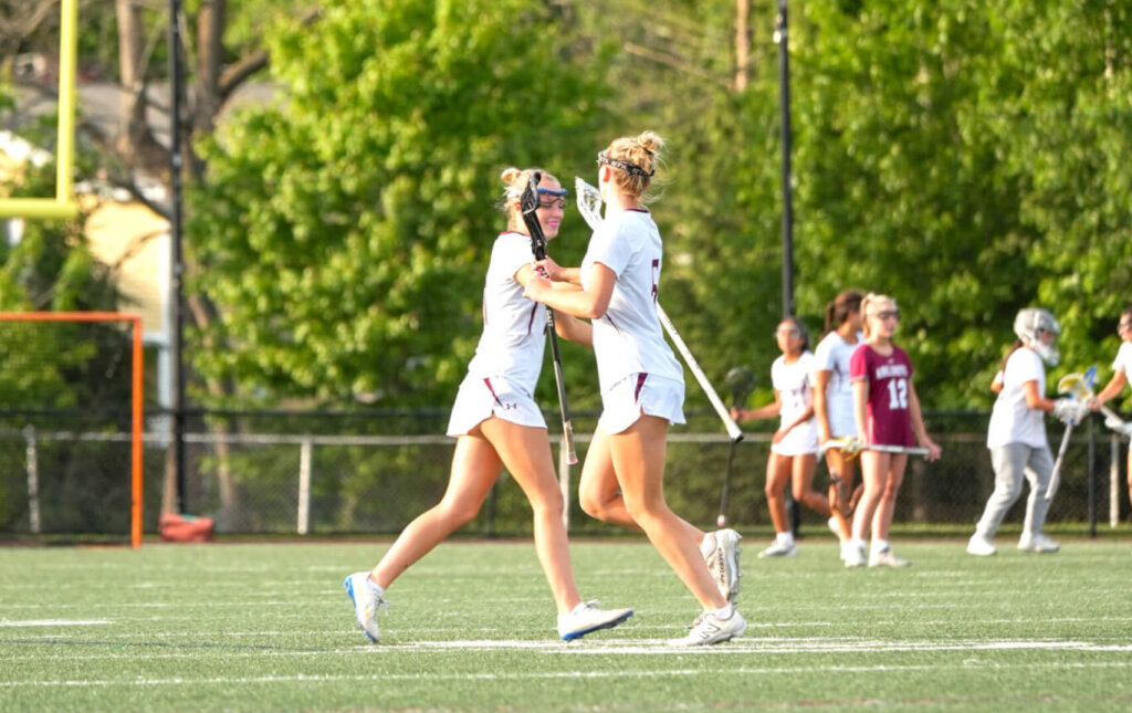 Acton-Carlisle sophomore teammates Scarlett Mirak (right) and Lindsay Cain (left) tap sticks while subbing on/off during the round of 32 playoff game against Arlington. Photo by Aidan Moroney
