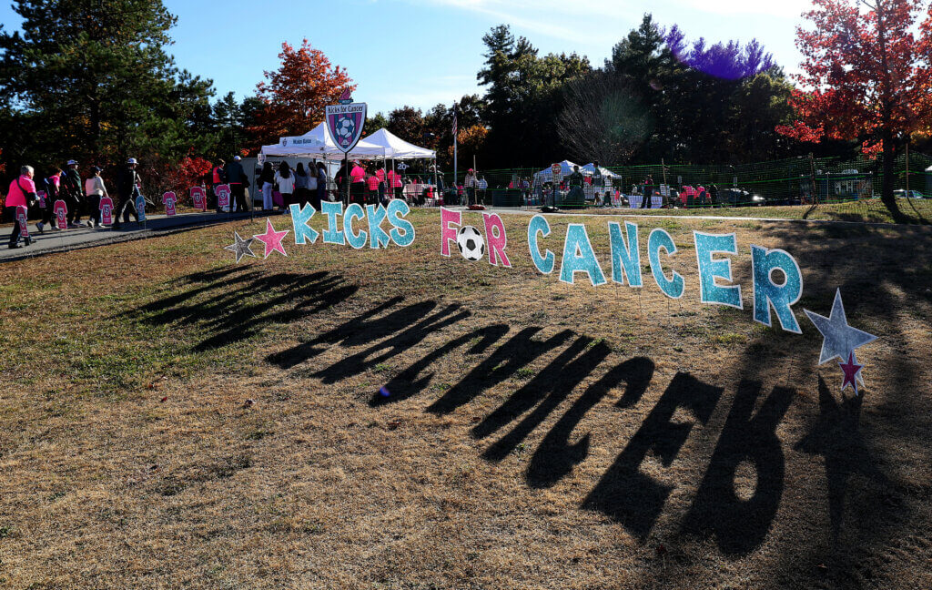 The Kicks for Cancer sign casts shadows and welcomes fans.