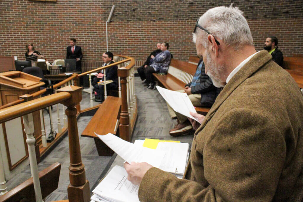 John Grace flips through a binder of legal cases, news clippings, emails, and other printouts before his latest court appearance. Photo: Dakota Antelman/The Acton Bridge