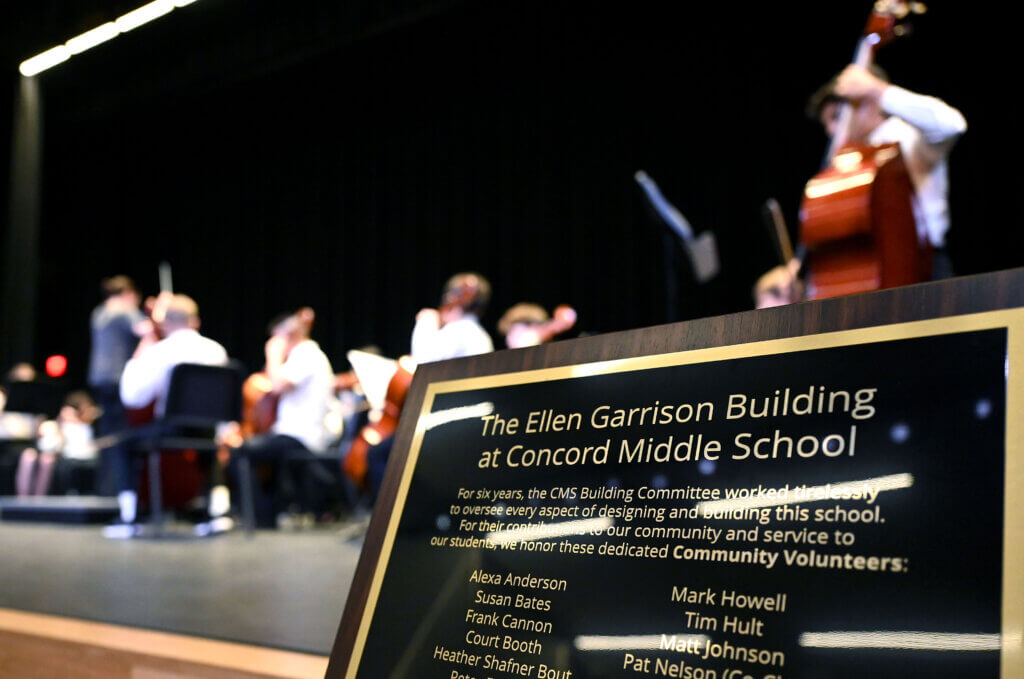 A plaque for the Ellen Garrison Building at Acton Middle School sits on the stage as the Acton Middle School orchestra performs in the auditorium on Wednesday, June 11, 2025. Ken McGagh/The Acton Bridge