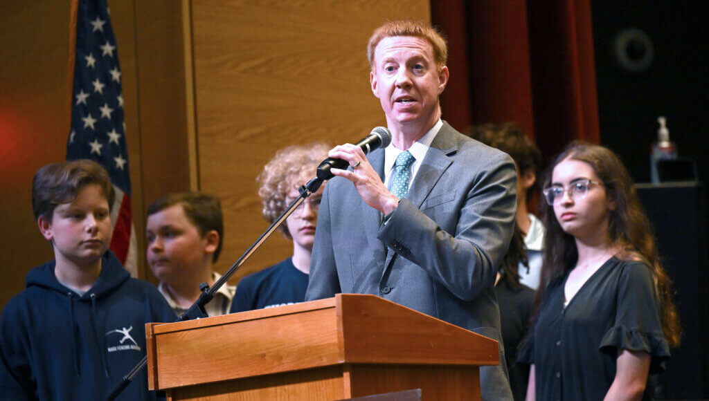 Justin Cameron, principal of the Ellen Garrison Building at Acton Middle School, speaks during a ribbon cuttting program for the new school on Wednesday, June 11, 2025. Behind him are some of the members of the school’s Student Building Committee. Ken McGagh/The Acton Bridge