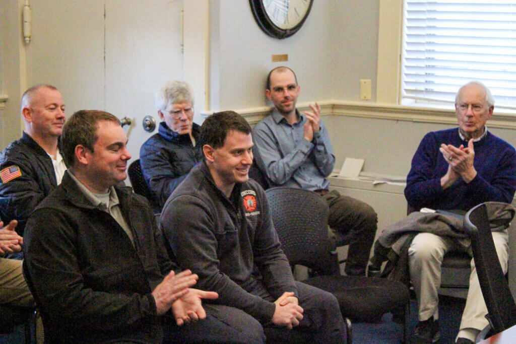 Firefighter Jesse Caney smiles as colleagues applaud his Select Board commendation for helping an unconscious woman on a March 12 redeye flight. Photo: Dakota Antelman/The Acton Bridge
