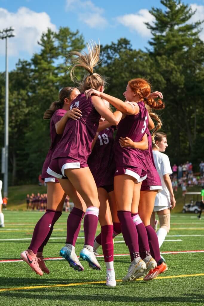 Acton-Carlisle High School captain Braeden Peca (middle right) celebrates with her teammates after scoring the first goal of the game against Walpole. Photo by Aidan Moroney