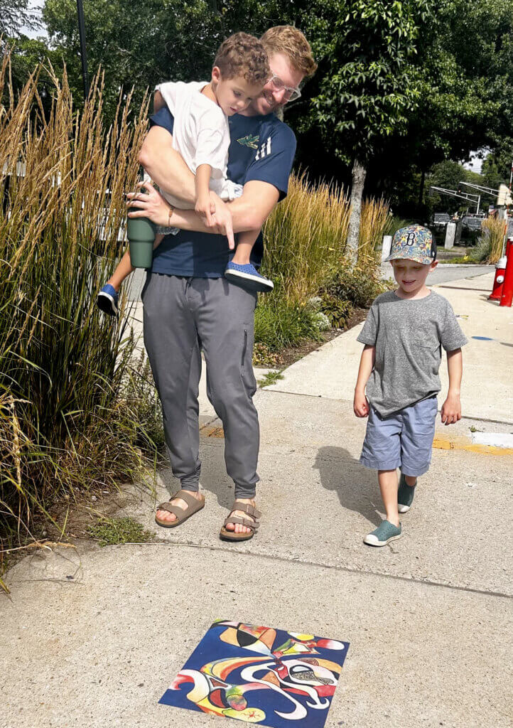 Paul Nelson with Spencer (4) and Everett (7) Mauk stop to look at Yvonne Sandell’s painting “Let’s Eat.” Courtesy photo