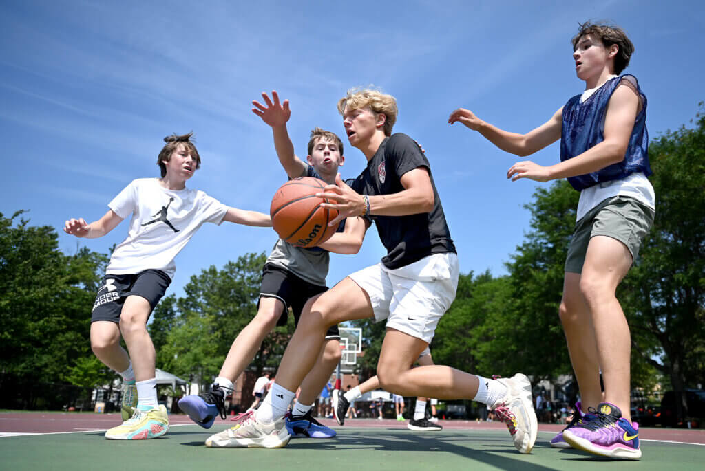 Burke Breimyer, 14, a rising freshman at Acton-Carlisle High School, drives to the hoop during a one-day 3v3 basketball tournament to raise money and awareness for NMDP, formerly known as the National Marrow Donor Program, a non-profit that manages a global bone marrow registry that finds donors for lifesaving bone marrow transplants, at Emerson Playground on Saturday, July 26, 2025. He was guarded by Ewan van der Swaagh, 15, right, a rising freshman at Acton-Carlisle High School who has been the recipient of two bone marrow transplants via the NMDP registry. $3,100 was raised Saturday. Ken McGagh/The Acton Bridge