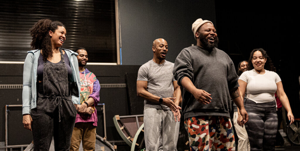 “Hairspray” cast members and director Najee Brown (fourth from left) laugh during rehearsals. Photo by Jim Sabitus
