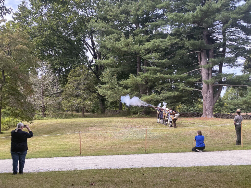 A musket salute by volunteers from the Friends of Minute Man National Park, after the conclusion of speeches at the event. Photo by Alden Parker