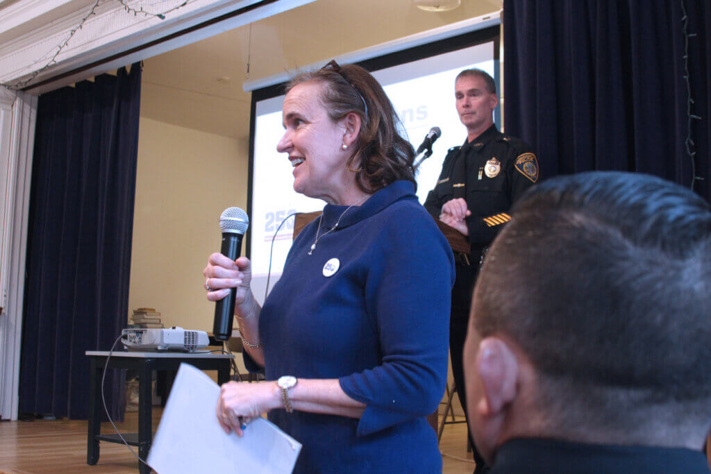 Concord250 organizer Polly Meyer speaks during a March 14 meeting while Acton police Capt. Brian Goldman (top) and police business liaison Steve Hawkins (bottom) look on. Photo: Dakota Antelman/The Acton Bridge