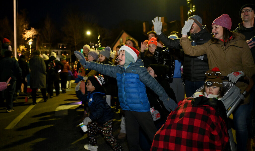 The crowd waves as the tree lighting parade makes its way down Main Street.
