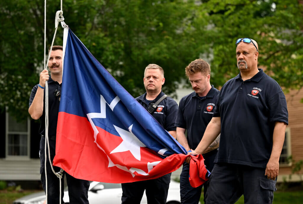 Members of the Acton Fire Department prepare to raise the Juneteenth flag.