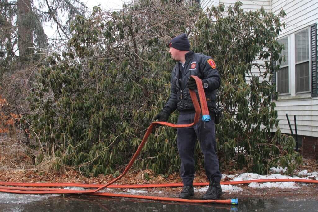 Pic 6: A firefighter manages a hose Friday morning while crews remained on scene at the site of a house fire on Cottage Lane. Photo: Dakota Antelman/The Acton Bridge