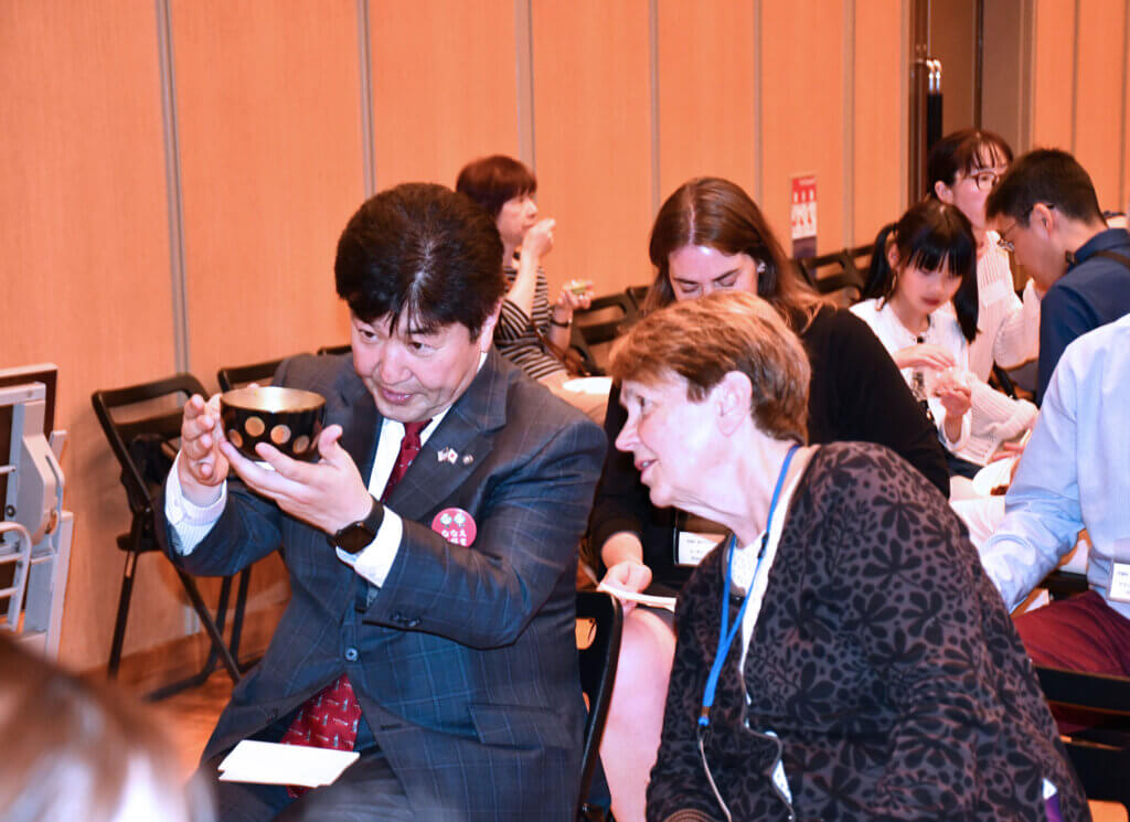Nanae Mayor Futoshi Sugihara shows Select Board member Mary Hartman how to hold a cup for a tea ceremony. Photo courtesy of Jack Brox McCarthy