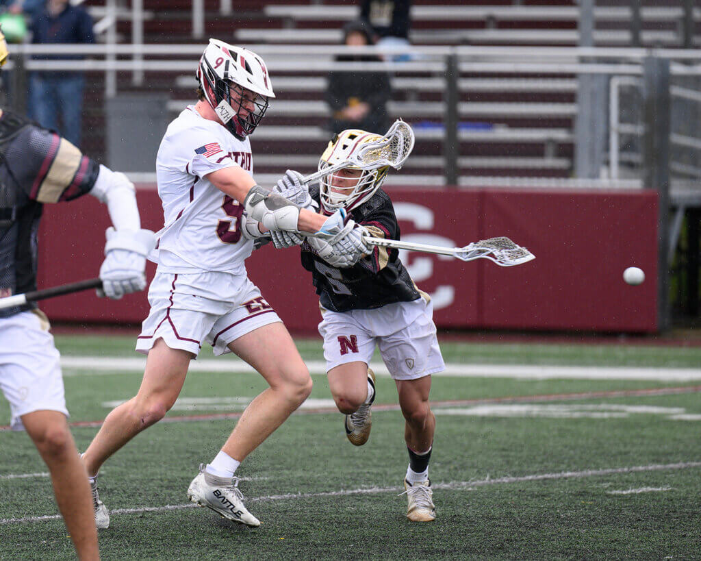 Acton-Carlisle’s Peter Burke (No. 9) shoots and scores with Newburyport’s Ben Buchmayr (No. 6) defending during last Saturday’s Senior Day game. Photo by Jon Straggas