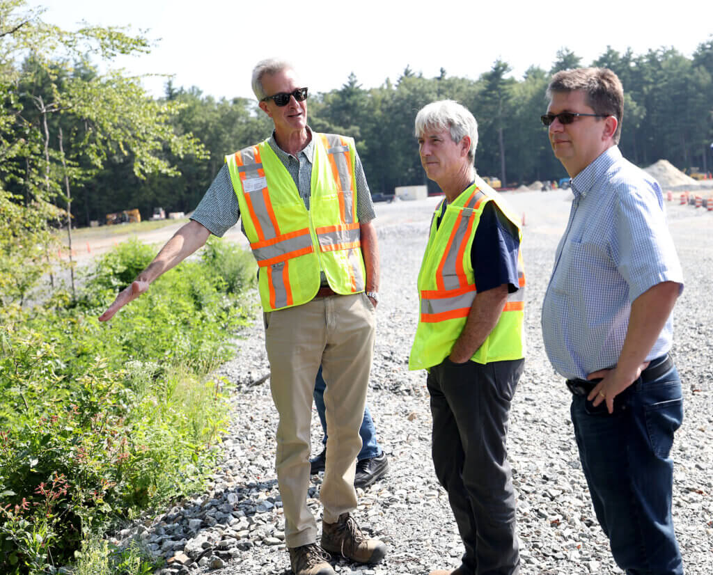 Bruce Thompson, project coordinator for the Superfund site cleanup, speaks as DPW director Alan Cathcart, center, and Sven Weber, right, co-chair of the Land Use Working Group, listen during a site visit at the 2229 Main Street Superfund Site in Acton on Wednesday, August 13, 2025. Ken McGagh/The Acton Bridge