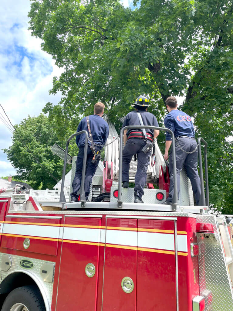 Acton firefighters assess the situation before returning two baby starlings to their nest. Courtesy photo