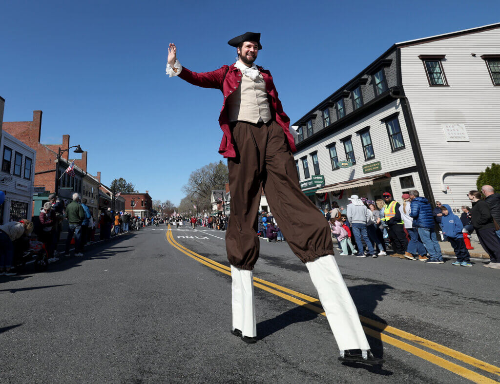 Dressed in Colonial garb, stilt walker Jay Reilly waves to the Acton Center crowd. 
