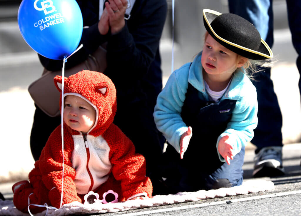 Rosie Mackay, 3, and her sister Violet, 1, of Chelmsford, watch the parade in Acton, where their grandparents live.  
