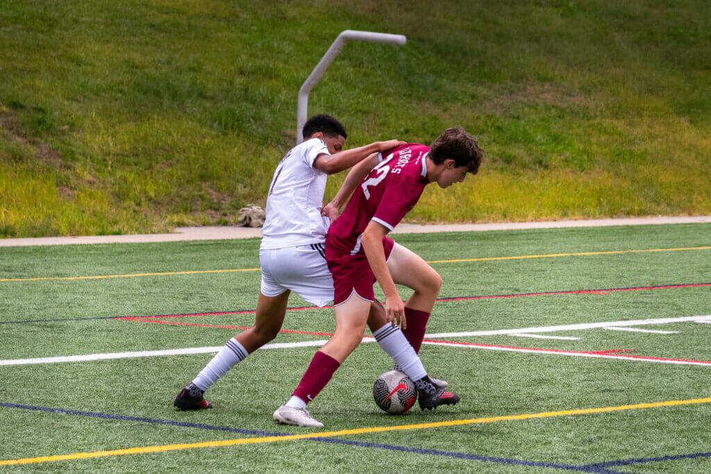 Acton-Carlisle's Peter Brown (No. 22) defends against Dearborn STEM Academy on September 8. Photo by Rocco Miccechi