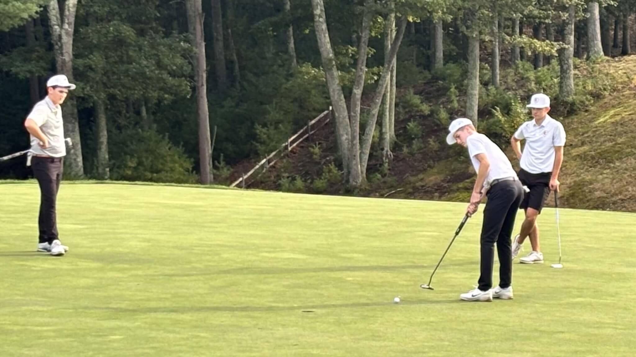 Ben Brooks putts on the fourth green at Acton Country Club as Acton-Carlisle co-captain Glen Murdough, right, and a Wellesley opponent look on during their September 30 match. Photo by Carl Sweeney