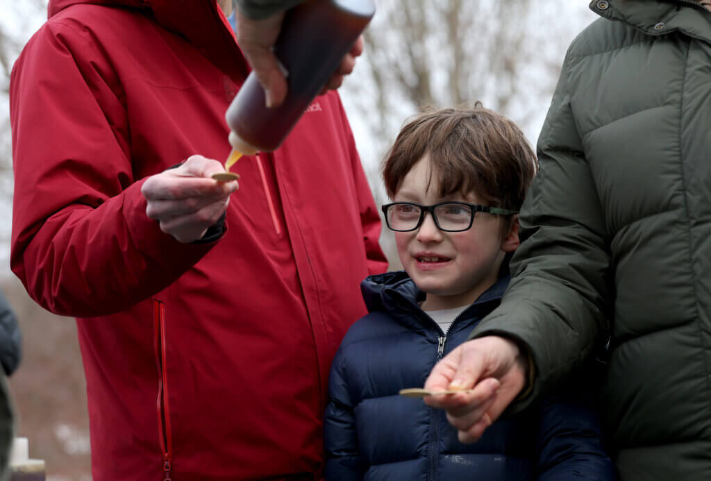 Silas McNamara, 7, of Acton, watches as his parents, Lindsay Ludwig and Brian McNamara, sample Gaining Ground maple syrup during an open house on Saturday, March 7, 2026. Ken McGagh/The Acton Bridge