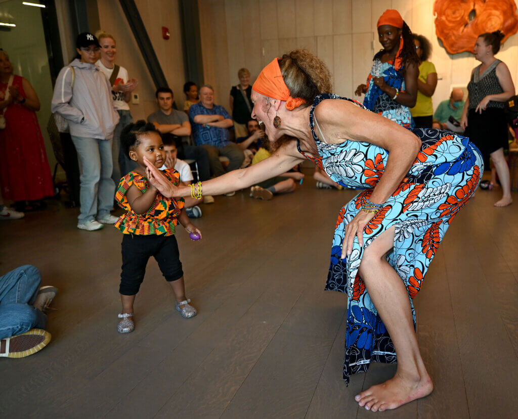 Tara Murphy, director of Ammaya Dance & Drum, high-fives Namarie Charles, 2, of Acton, the niece of Scynthia Charles, a dancer in the group.