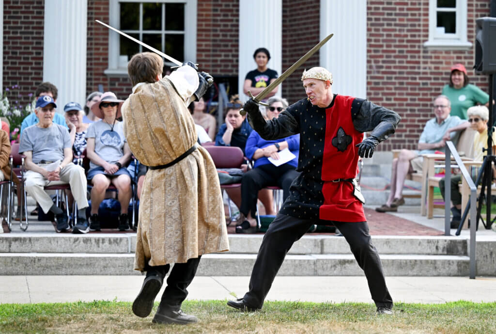 Julian Willard, right, as Sir Walter Blunt, and Ben Martin, as the Earl of Douglas engage in a sword fight during The World’s A Stage Players production of William Shakespeare’s “Henry IV, Part I” on the Acton Free Public Library lawn on Saturday, July 26, 2025. Two more outdoor performances are scheduled for August 2 and 3 at the library. Ken McGagh/The Acton Bridge