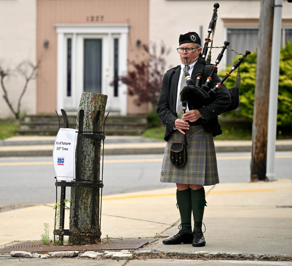 Brian Quirk plays the bagpipe at the site of a future 250th tree.
