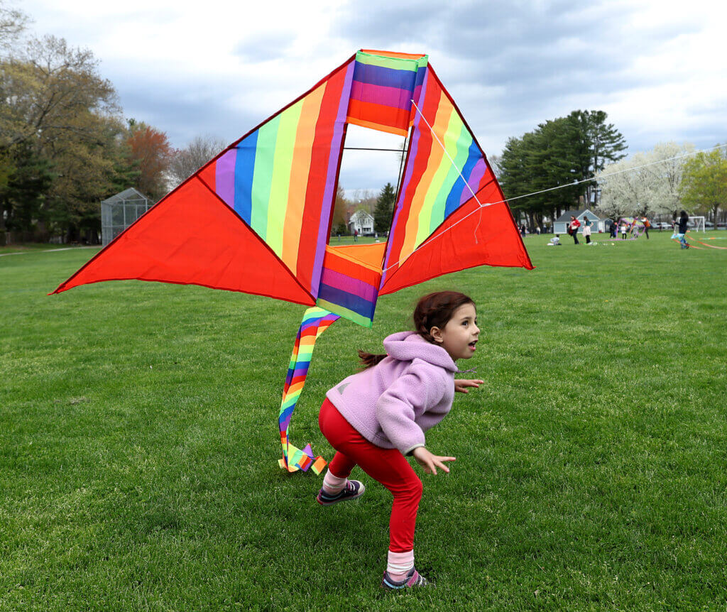 Maia Devlin, 5, of Acton, ducks as her mother Giselle Devlin launches her kite during the Acton Recreation Department’s Kite Festival at Rideout Park in West Acton on Saturday, May 2, 2026. Ken McGagh/The Acton Bridge