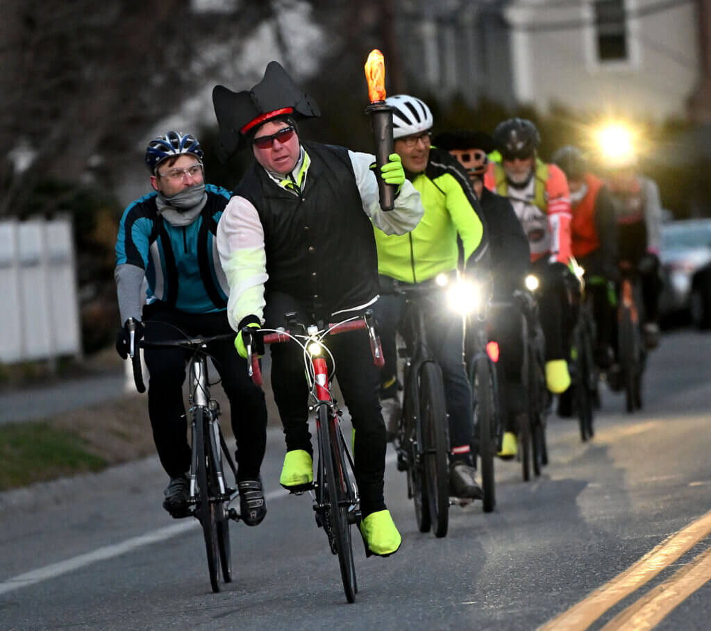 Tim Wilson of Wilmington carries an LED torch as a procession of cyclists completes a journey from Boston’s North Church to the Acton Museum. Photo: Ken McGagh/The Acton Bridge
