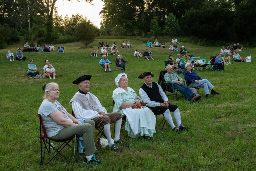 People sit in lawn chairs to watch the performance. Minute Man National Historical Park, cannon firing in honor of the Declaration of Independence. Jon Chase photo
