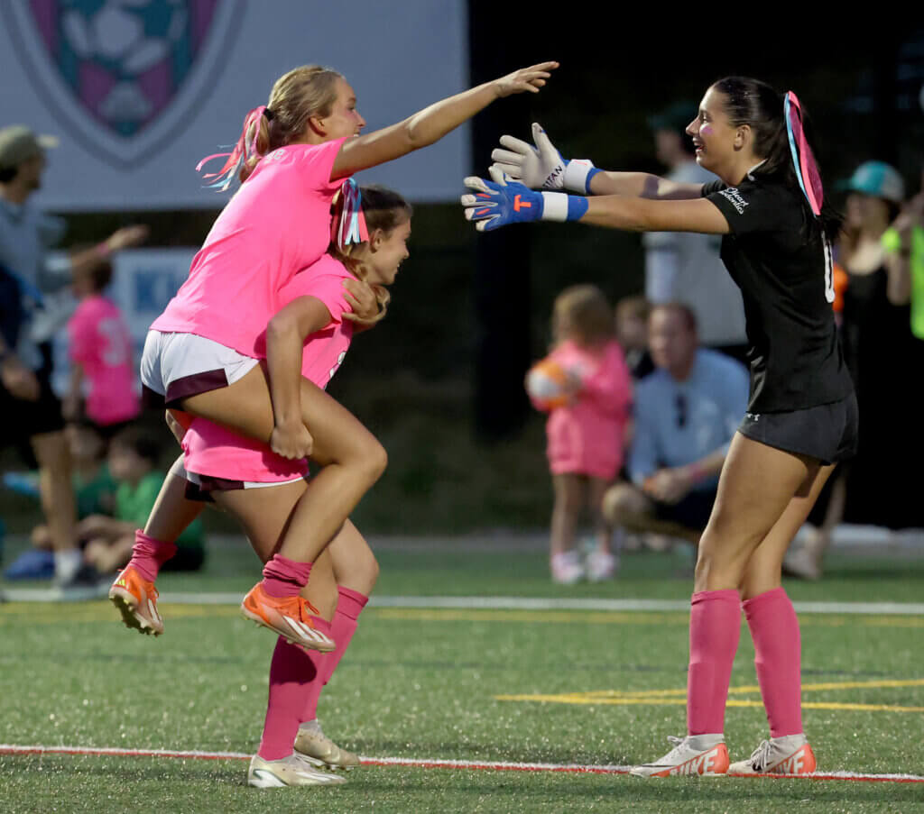 Kendall Johnson, left, gets a lift from a teammate as she and goalie Aubrey Monaghan celebrate the Patriots’ dramatic victory.
