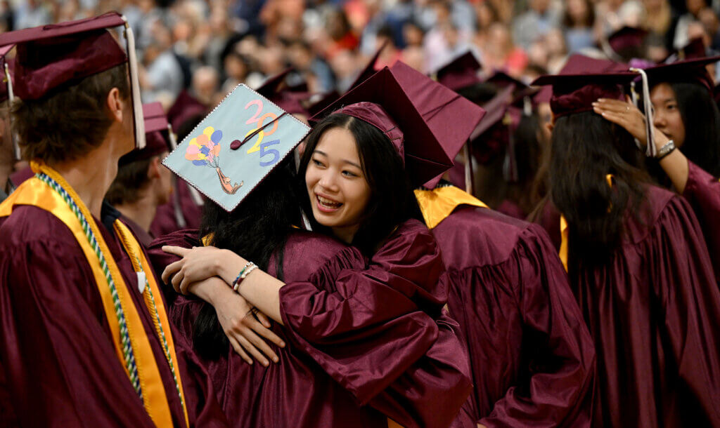 Graduates share a warm hug at Saturday’s commencement. Photo: Ken McGagh/The Acton Bridge 
