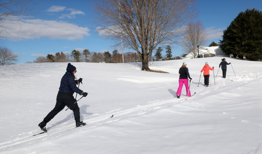 From left, Jen Rossi, Heather Halsey, Julie Gibowicz, and Jodi Sparks cross-country ski under blue skies at Nashawtuc Country Club on Tuesday. Nashawtuc Country Club regularly grooms trails on its grounds for the enjoyment of local cross-country skiers. Photo: Ken McGagh/The Acton Bridge