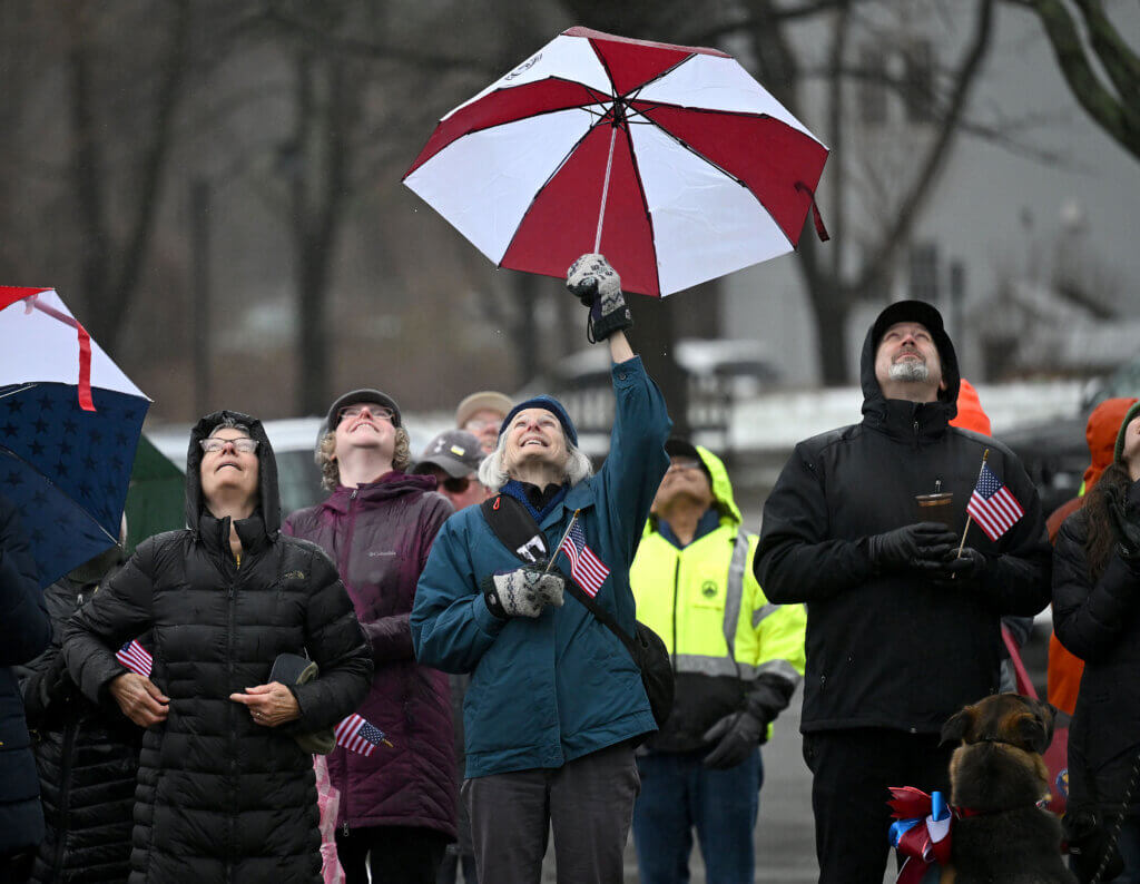 Concordians look skyward to admire the town’s new oversized American flag during a flag-raising ceremony in Acton Center on Saturday, April 12, 2025.  Ken McGagh/The Acton Bridge