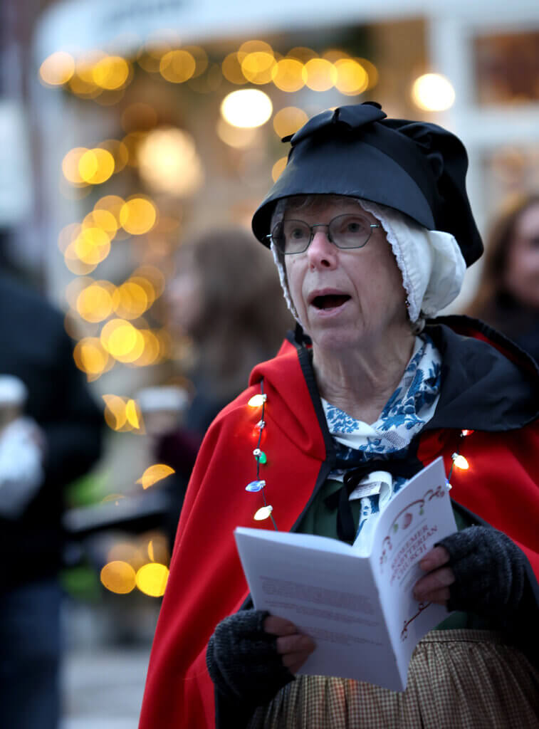 Karen Ahearn of the Acton Minute Men sings along with the Redeemer Presbyterian Church choir during the town’s annual Tree Lighting on Sunday, December 7, 2025. Ken McGagh/The Acton Bridge