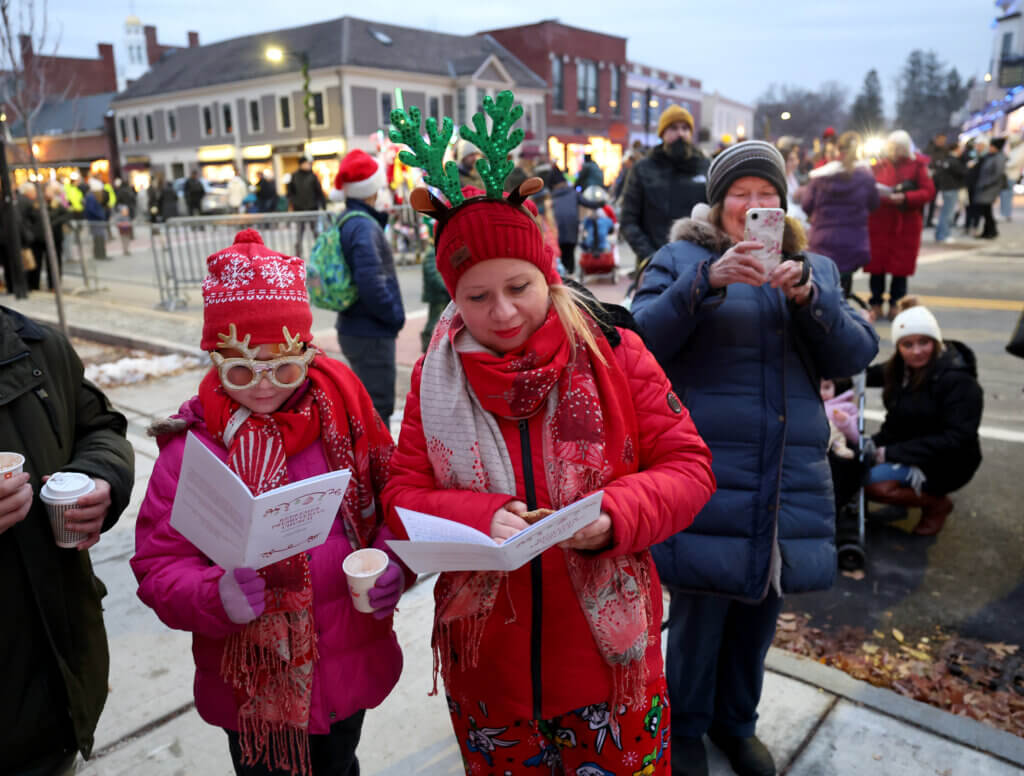 Decked out from head to toe in holiday attire, Ellen Farmer of Acton and her daughter Vera, 9, sing along to the Redeemer Presbyterian Church during the town’s annual Tree Lighting on Sunday, December 7, 2025. Ken McGagh/The Acton Bridge