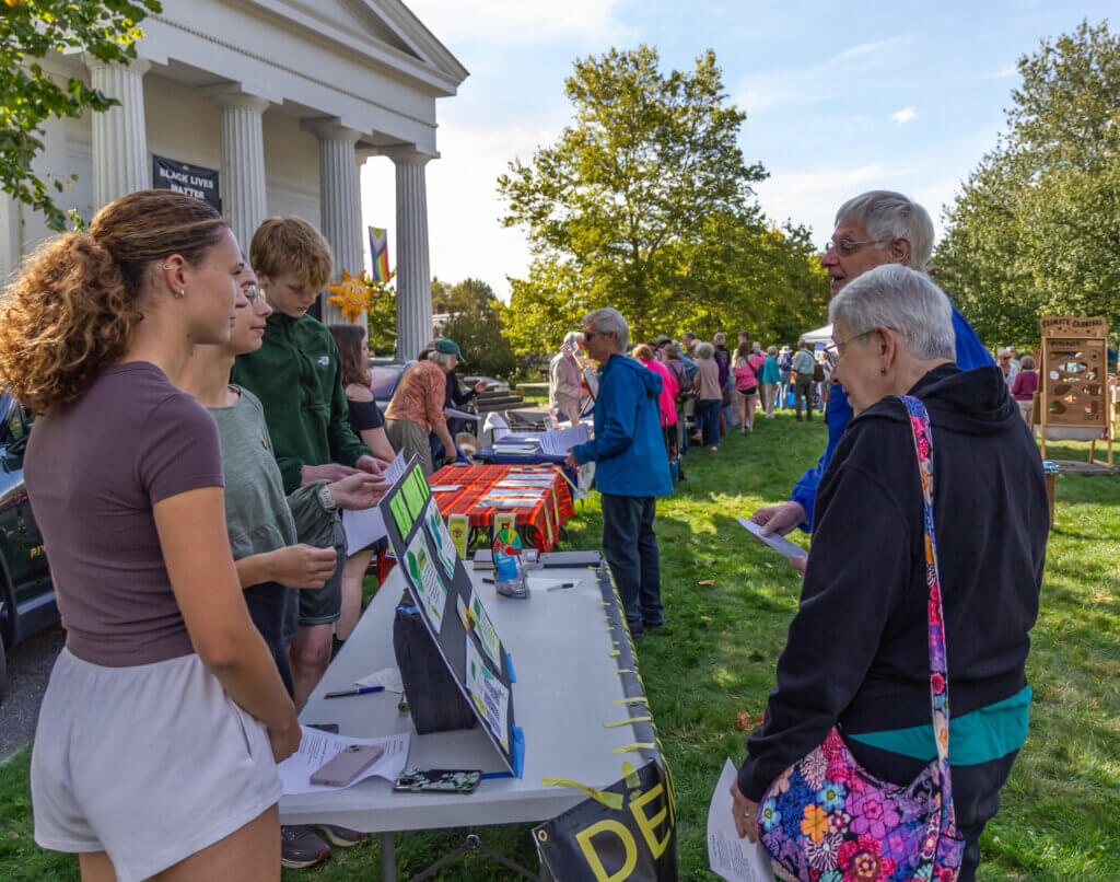 Members of Acton-Carlisle High School's Sunrise Movement – Audrey Benson, Iliana Benson, and Evan Hultgren – speak with interested visitors. Photo by Rebecca Woodward