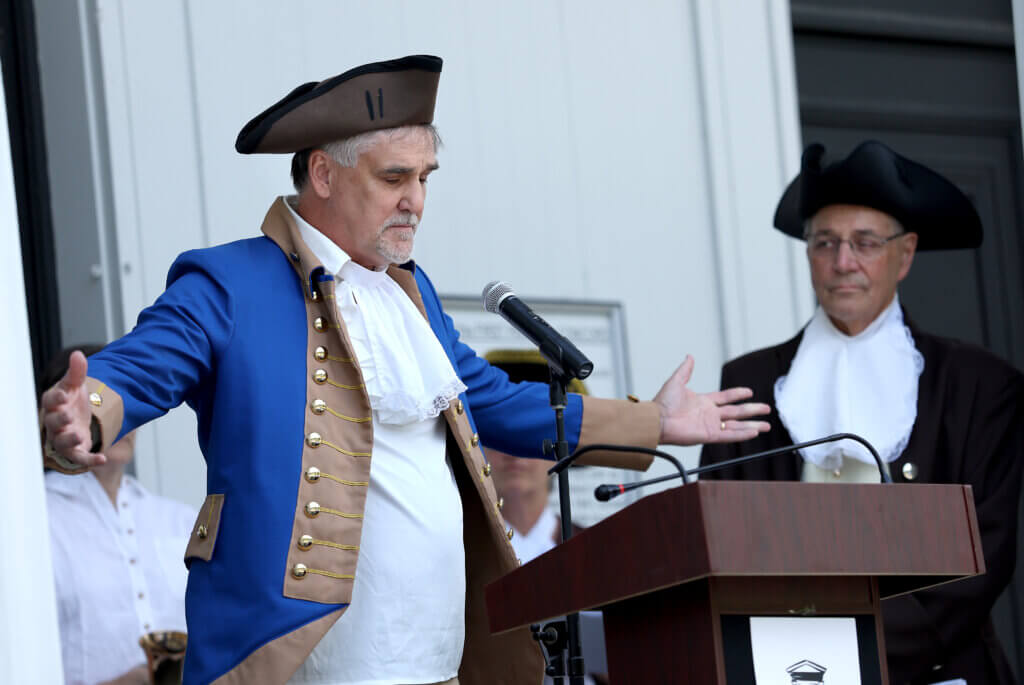 Rob Morrison of Acton, portraying Rev. William Emerson, pastor of the First Parish in Acton in 1776, gestures during his reading of the Declaration of Independence on Saturday, July 11, 2026. Ken McGagh/The Acton Bridge