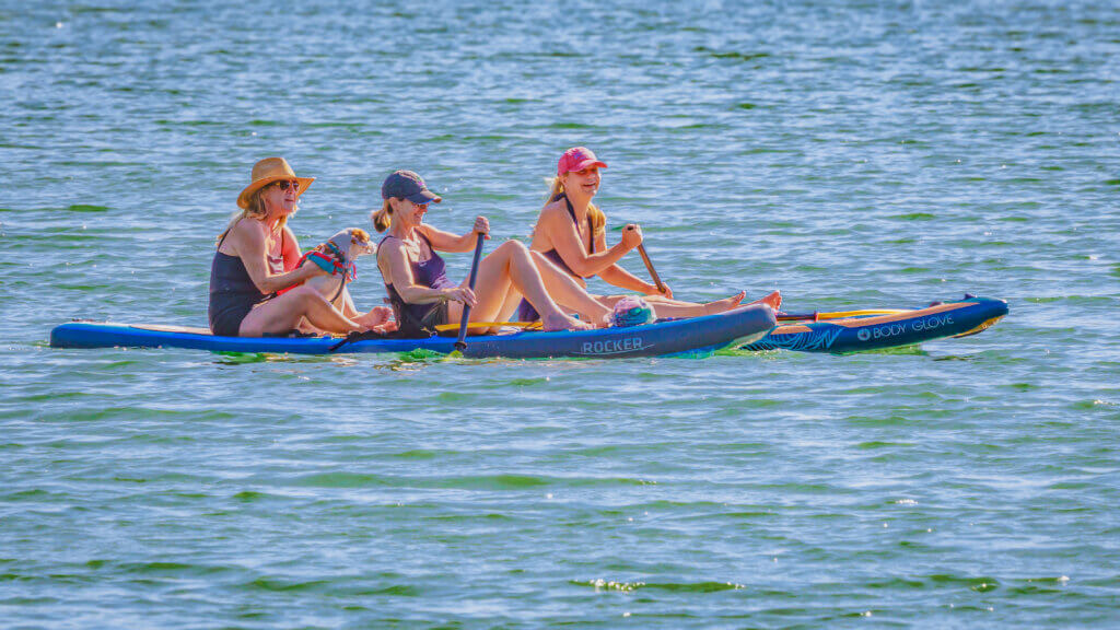 Acton friends — from left, Bee Mandell-Chayrigues, Rachel Stone, and Caroline Minkin — enjoy a peaceful end-of-day excursion, along with Rachel’s pooch Millie, who is forgoing the traditional dogpaddle. Photo by Jean Fain