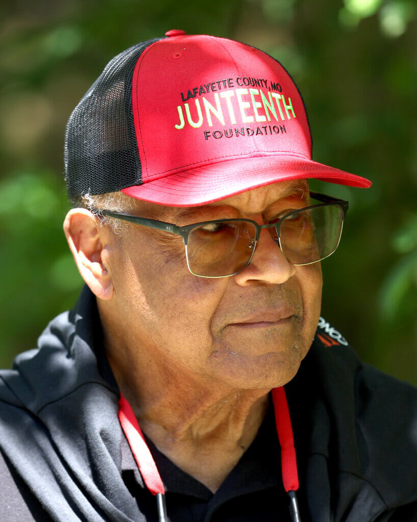 Ray Anthony Shepard of Lincoln, wearing a hat from last year’s Juneteenth celebration in Lafayette County, Missouri, listens to a band perform.  
