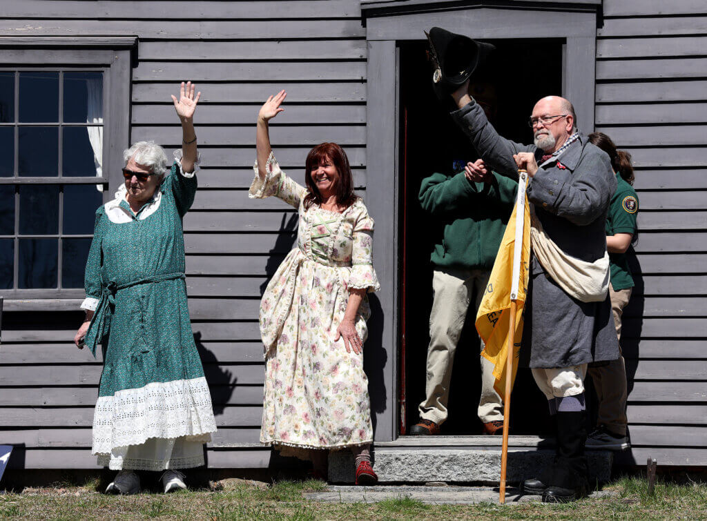 Merriam descendants including Allan Van Wert of Leominster, right, a seventh-generation descendent of Capt. Amos Merriam, wave from the steps of the Nathan Meriam House.

