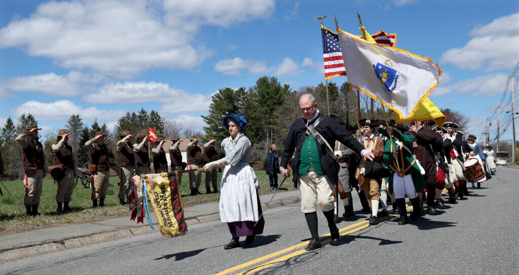 The Acton Minute Men pass the saluting members of the Acton Independent Battery as they march from the Ripley Building to the Nathan Meriam House.

