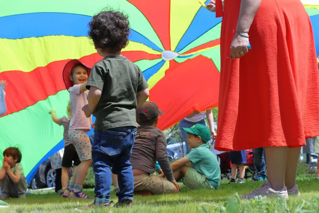 Alan Pinango, 2, watches as other kids play with a parachute. Photo: Trace Salzbrenner/The Acton Bridge