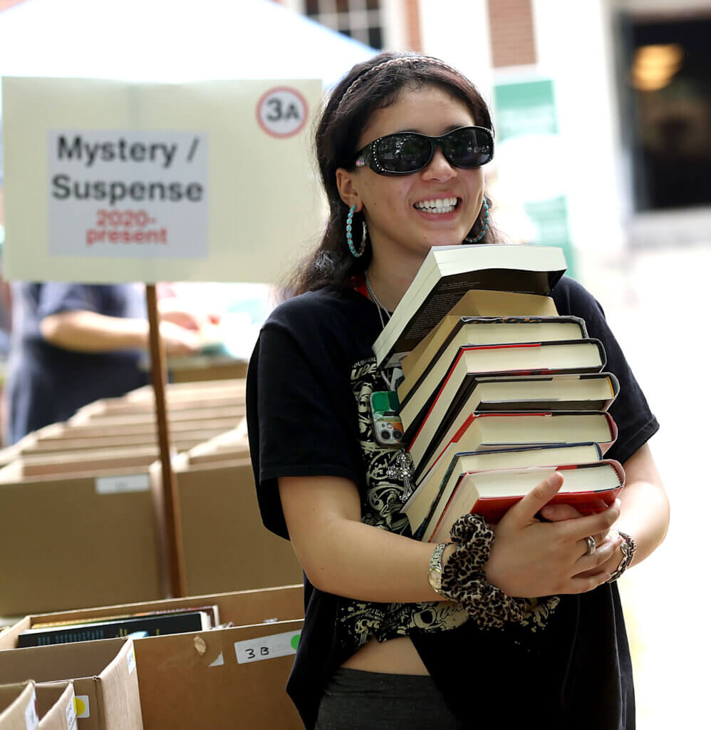 Naayah Isaac, 15, of Acton, hefts a stack of hardcovers and paperbacks.